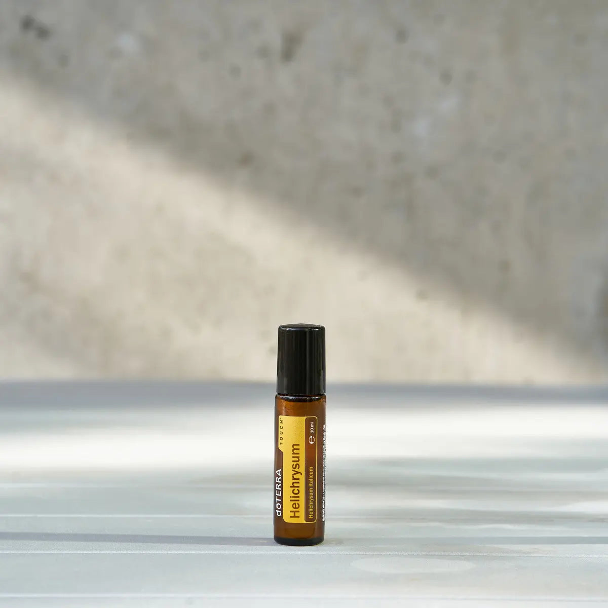 Helichrysum Touch doTERRA Roll-on 10ml — dois frascos com flores amarelas bokeh, óleo essencial regenerador CPTG