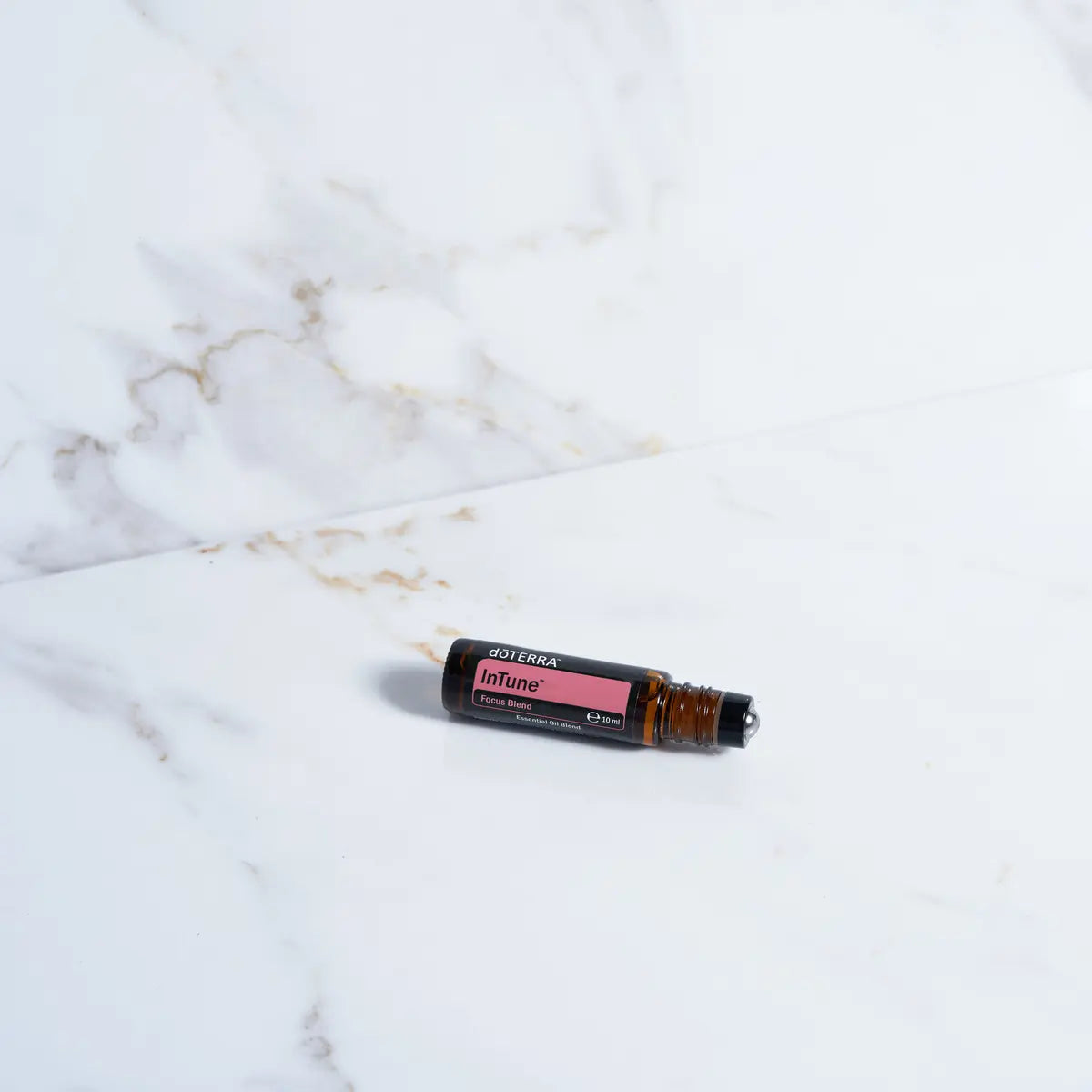 Roll-On InTune Touch doTERRA 10ml — frasco em estúdio fundo bege, mistura aromática para foco e clareza mental, óleo essencial CPTG