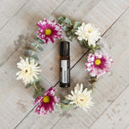 Roll-On Jasmim Touch doTERRA 10ml — coroa de crisântemos brancos e malvas em madeira vista de cima, óleo essencial CPTG
