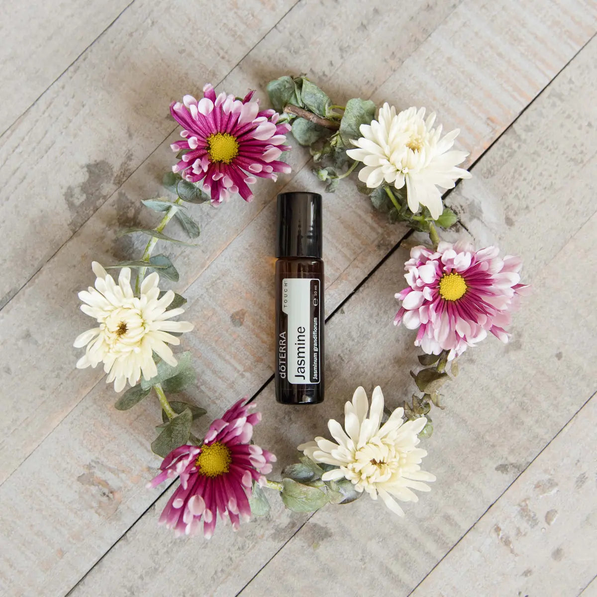 Roll-On Jasmim Touch doTERRA 10ml — coroa de crisântemos brancos e malvas em madeira vista de cima, óleo essencial CPTG