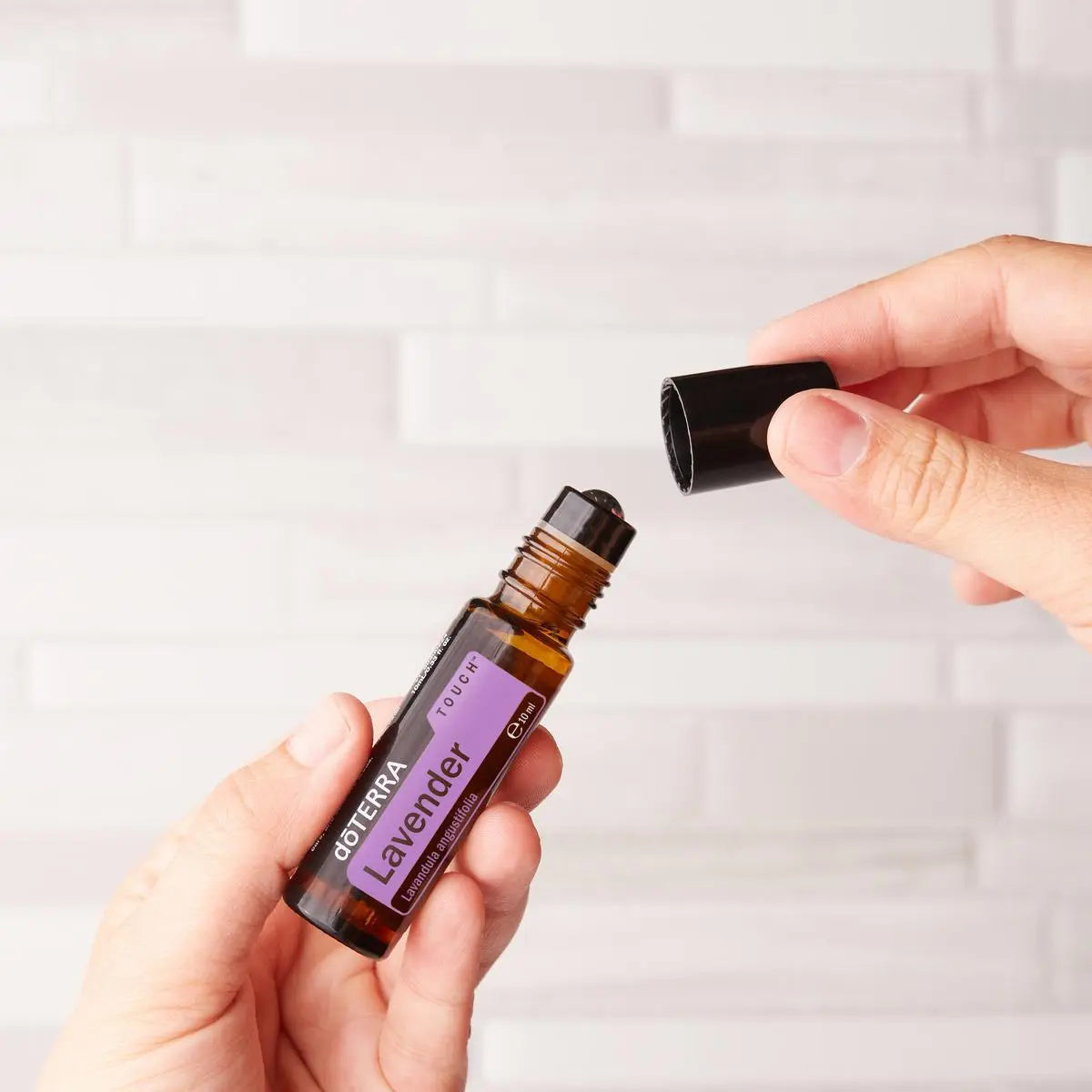 Roll-On Lavanda Touch doTERRA 10ml — mãos a abrir frasco parede de azulejo branco, óleo essencial lavanda doTERRA