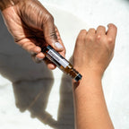 Roll-On Magnólia Touch doTERRA 10ml — mão de pele escura a aplicar no pulso em mármore, óleo essencial CPTG