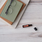 Roll-On Neroli Touch doTERRA 10ml — deitado com livros e óculos em madeira branca, óleo essencial neroli CPTG