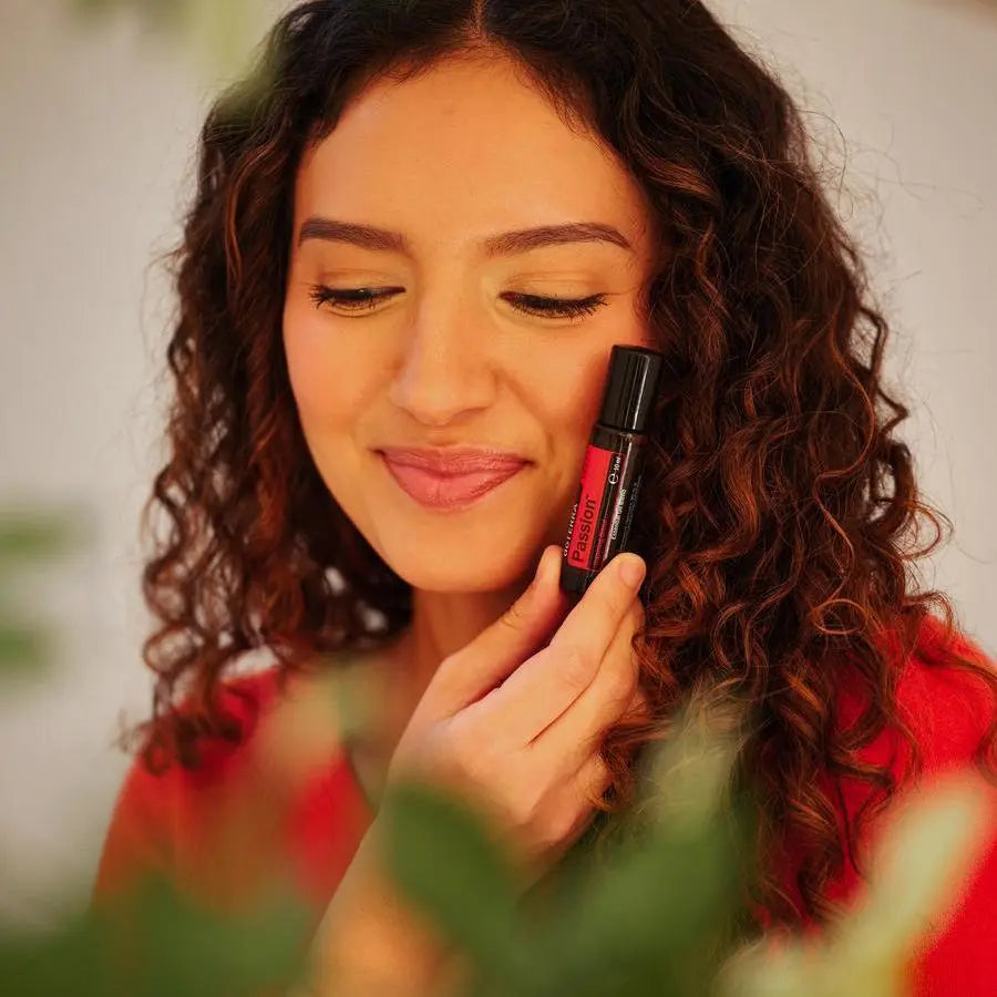 Roll-On Passion Touch doTERRA 10ml — mulher morena de cabelo encaracolado a aplicar com bokeh, aromaterapia