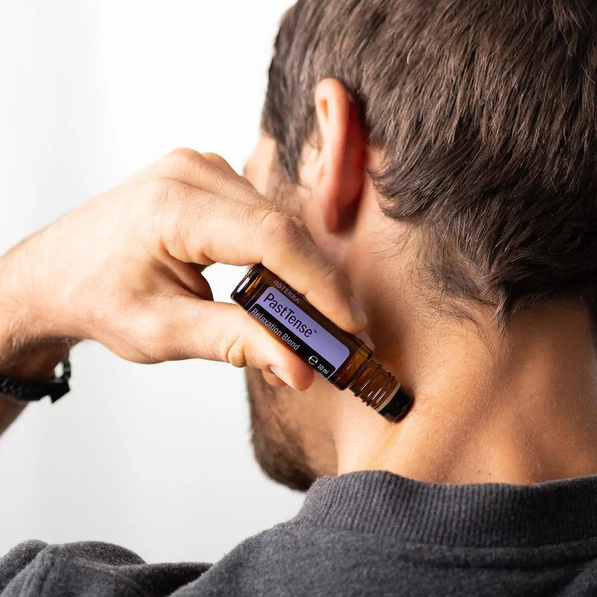 Roll-On PastTense doTERRA 10ml — homem a aplicar na nuca em primeiro plano, aromaterapia alívio tensão doTERRA