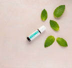 Tamer doTERRA Roll-On 10ml — diagonal com pau de rosa e folhas de hortelã vista de cima, mistura digestiva CPTG