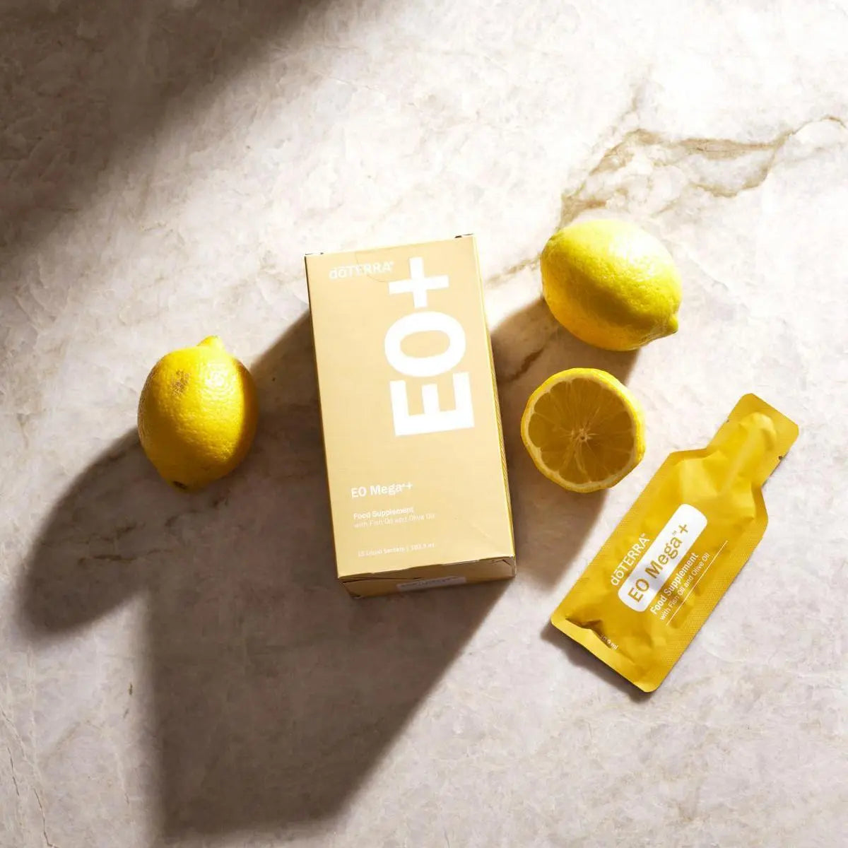 EO Mega+ doTERRA — caixa de saquetas com limões sobre mármore, vista cenital, suplemento ómega essencial