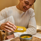 EO Mega+ doTERRA — homem sorridente a deitar saqueta em sopa, suplemento ómega essencial, bem-estar