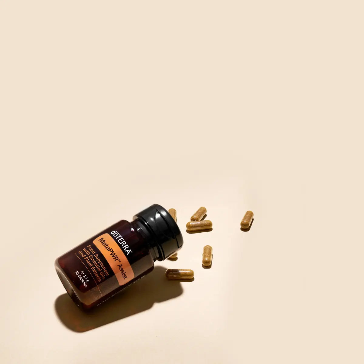 MetaPWR Assist doTERRA — frasco deitado com cápsulas sobre fundo bege, suplemento gestão de peso natural CPTG