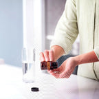 MetaPWR Assist doTERRA — mulher sorridente com frasco na cozinha, suplemento para controlo de peso natural CPTG