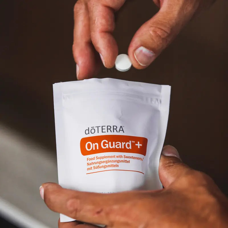 Pastilhas Mastigáveis On Guard+ doTERRA — mãos a segurar saco com pastilha em primeiro plano, suplemento imunidade natural