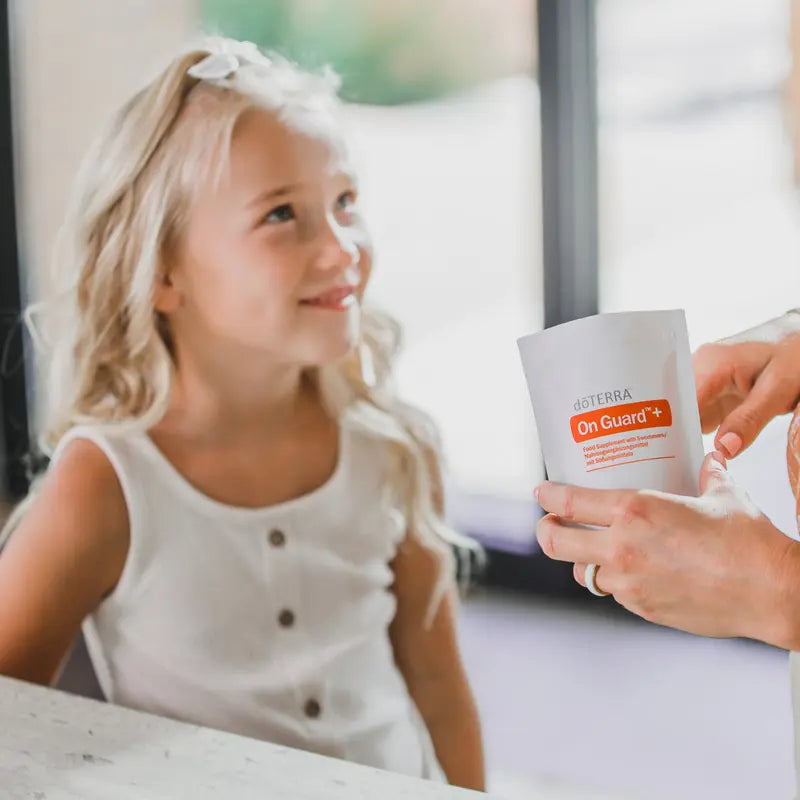 Pastilhas Mastigáveis On Guard+ doTERRA — menina loira com saco familiar, suplemento defesas naturais para toda a família