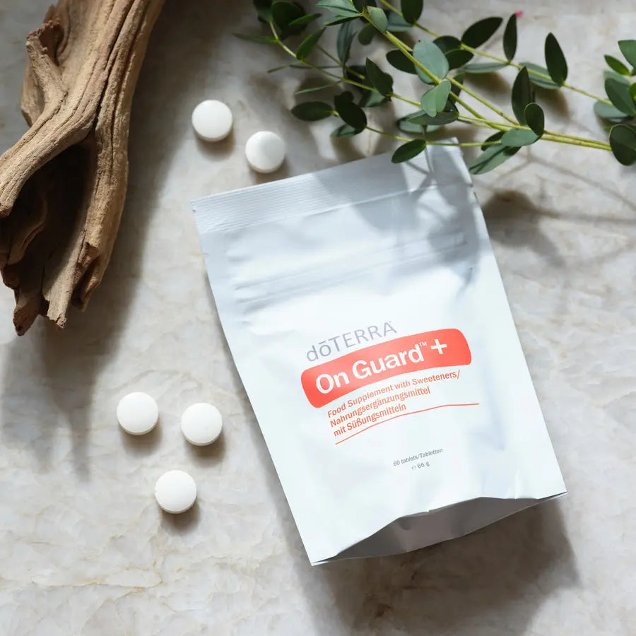 Pastilhas Mastigáveis On Guard+ doTERRA — saco com pastilhas sobre mármore e eucalipto, vista aérea, suplemento puro CPTG