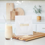 Proteína Vegetal Baunilha doTERRA 512g — saco com batido em tábua de madeira na cozinha, proteína vegetal pura CPTG