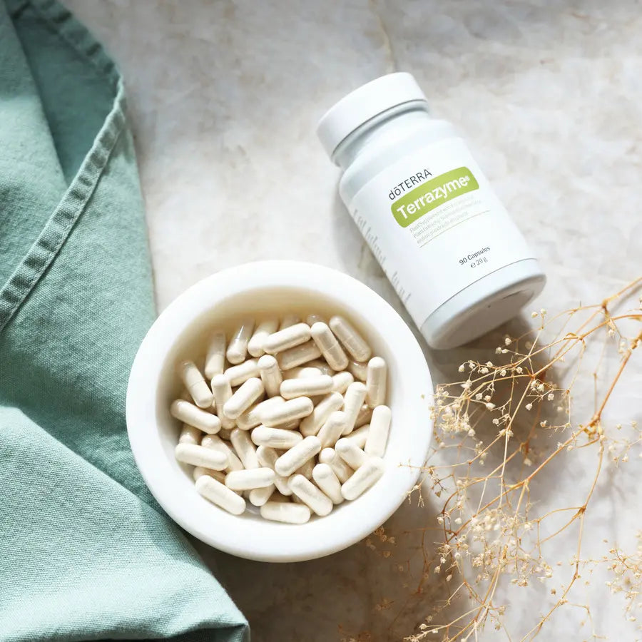 TerraZyme doTERRA 90 ct — cápsulas em tigela branca com flor seca, vista aérea, suplemento enzimas digestivas CPTG