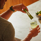 VMG+ doTERRA saqueta com homem preparando batido verde na cozinha — suplemento alimentar vegetal puro com nutrientes essenciais CPTG