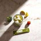 VMG+ doTERRA saqueta com vaso, brócolos, limão e morango em mármore vista de cima — suplemento alimentar vegetal puro CPTG