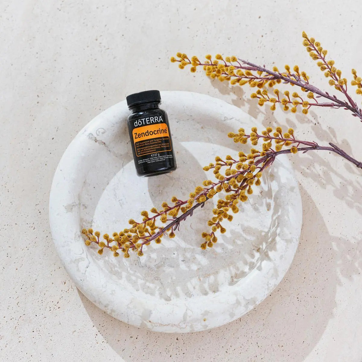 Cápsulas moles Zendocrine doTERRA frasco preto em prato de mármore com ramos secos — suplemento detox natural CPTG